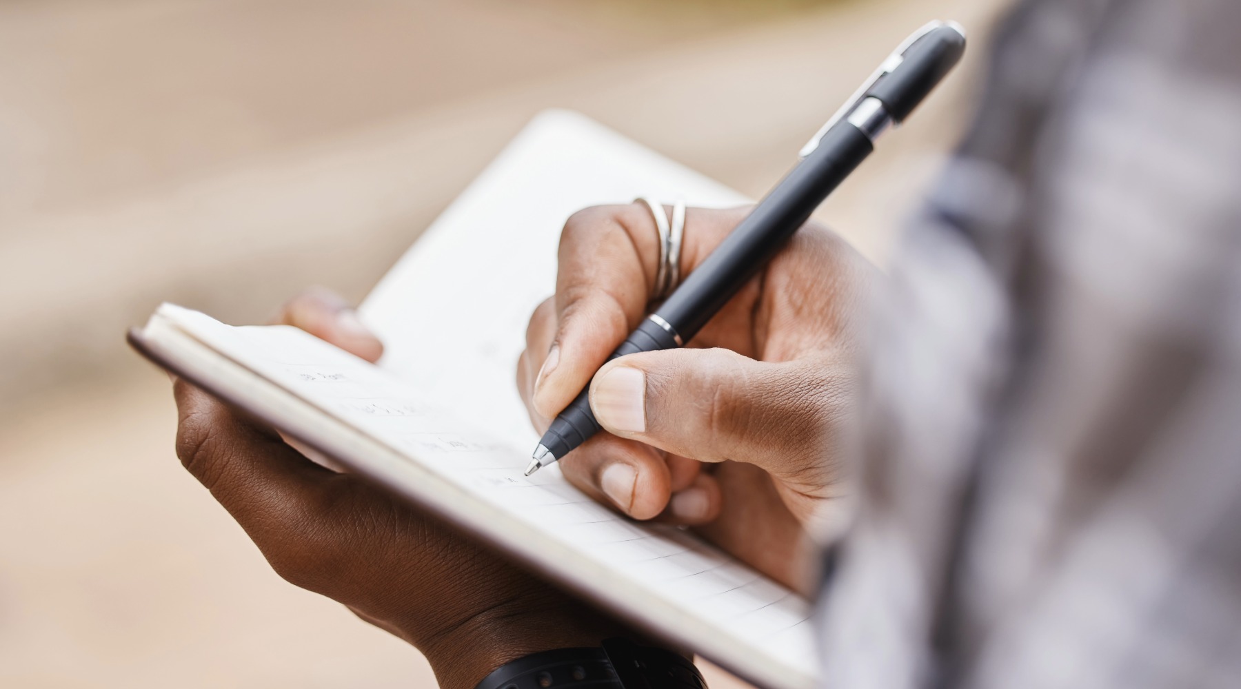 A man writing in a notebook with a pen.