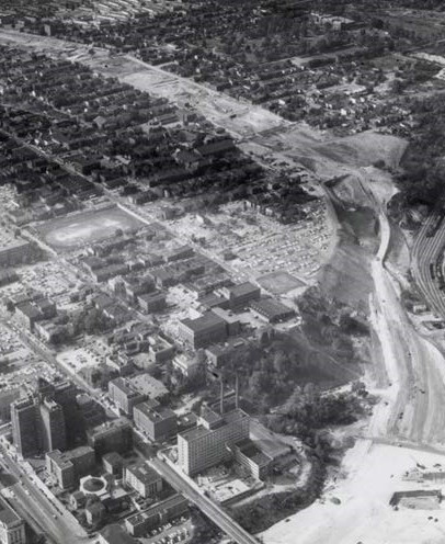 This image is a black and white photograph showing neighborhood destruction by freeway construction