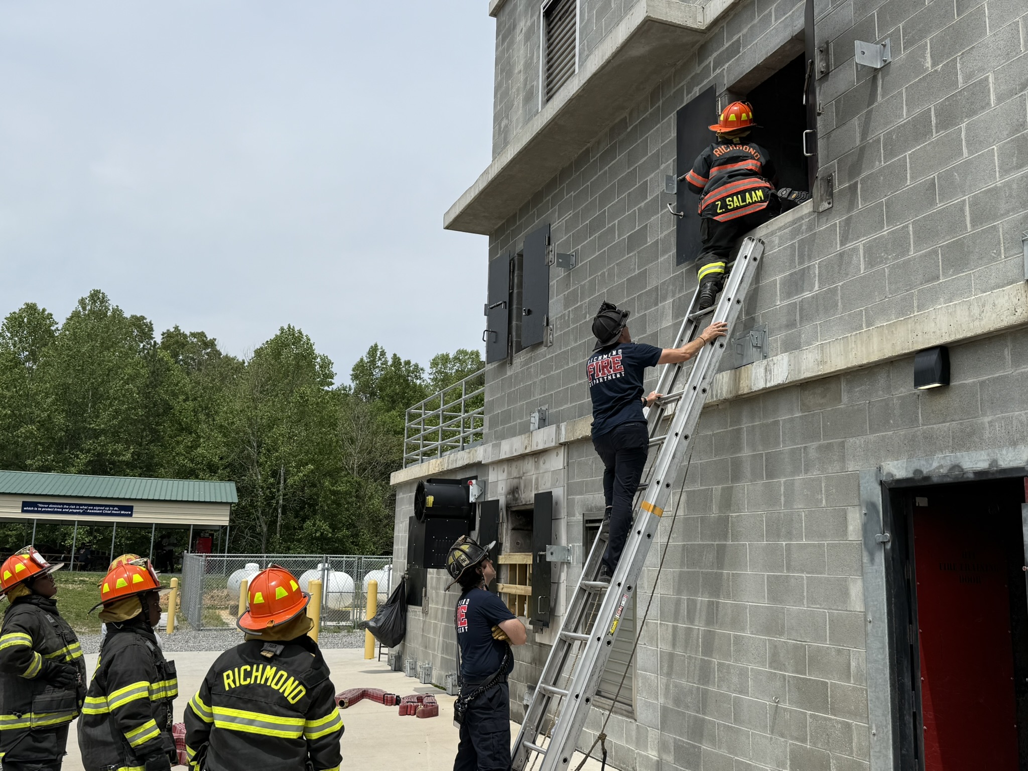 Firefighters climb a ladder into a building.